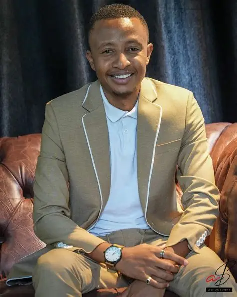 Smiling client in a tan Ashok suit on a leather chesterfield